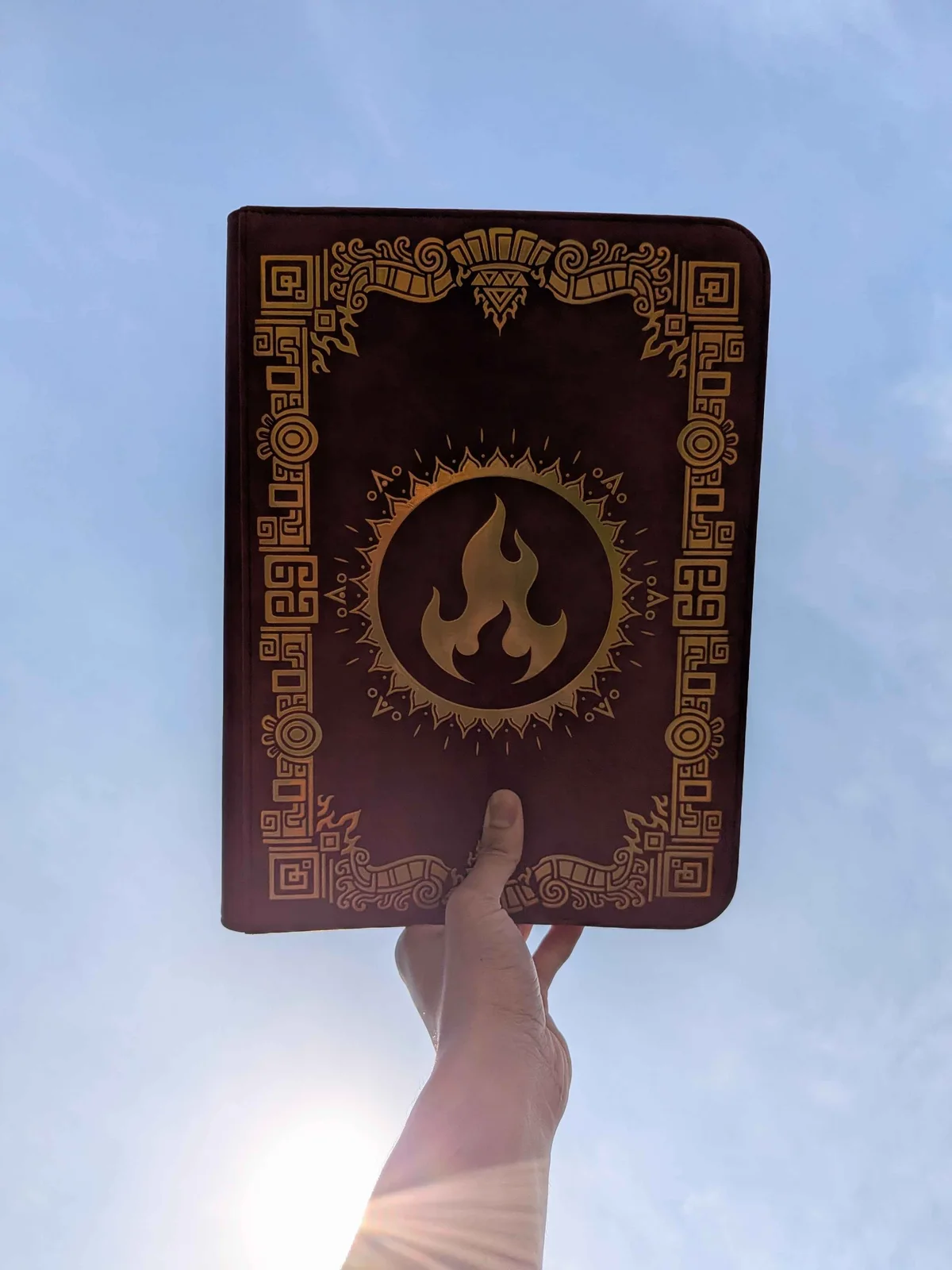 Sunfire binder held up against a blue sky in the sunlight